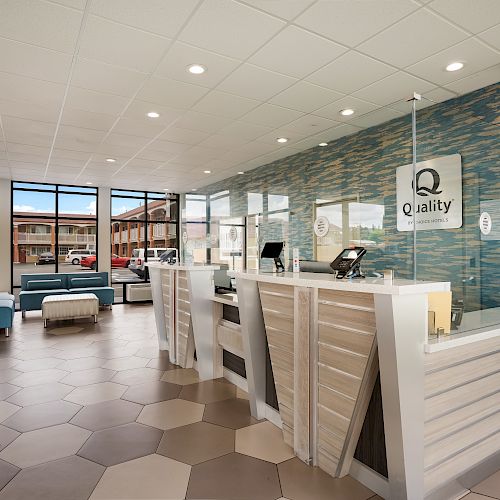 A modern hotel lobby with hexagonal floor tiles, a reception desk with partitions, blue cushioned seating, and large windows providing natural light.