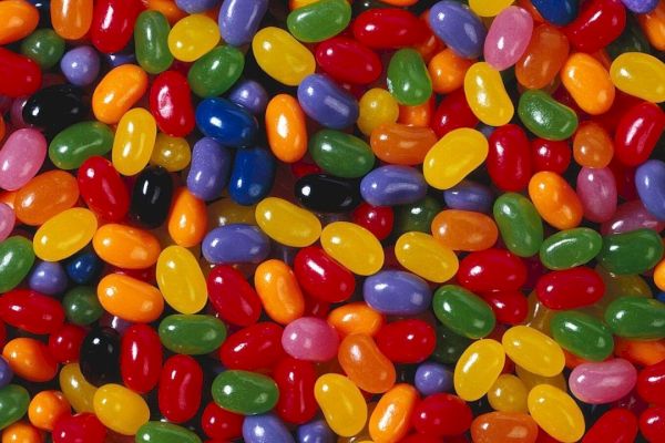 The image is filled with a variety of colorful jelly beans in different shapes and sizes, scattered randomly in a close-up view.